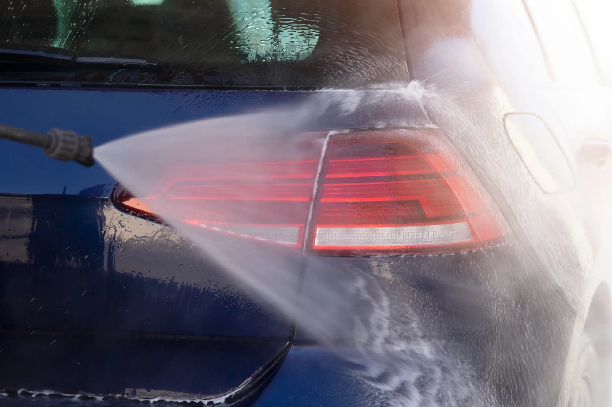 a woman washing it's blue car in a self service car wash